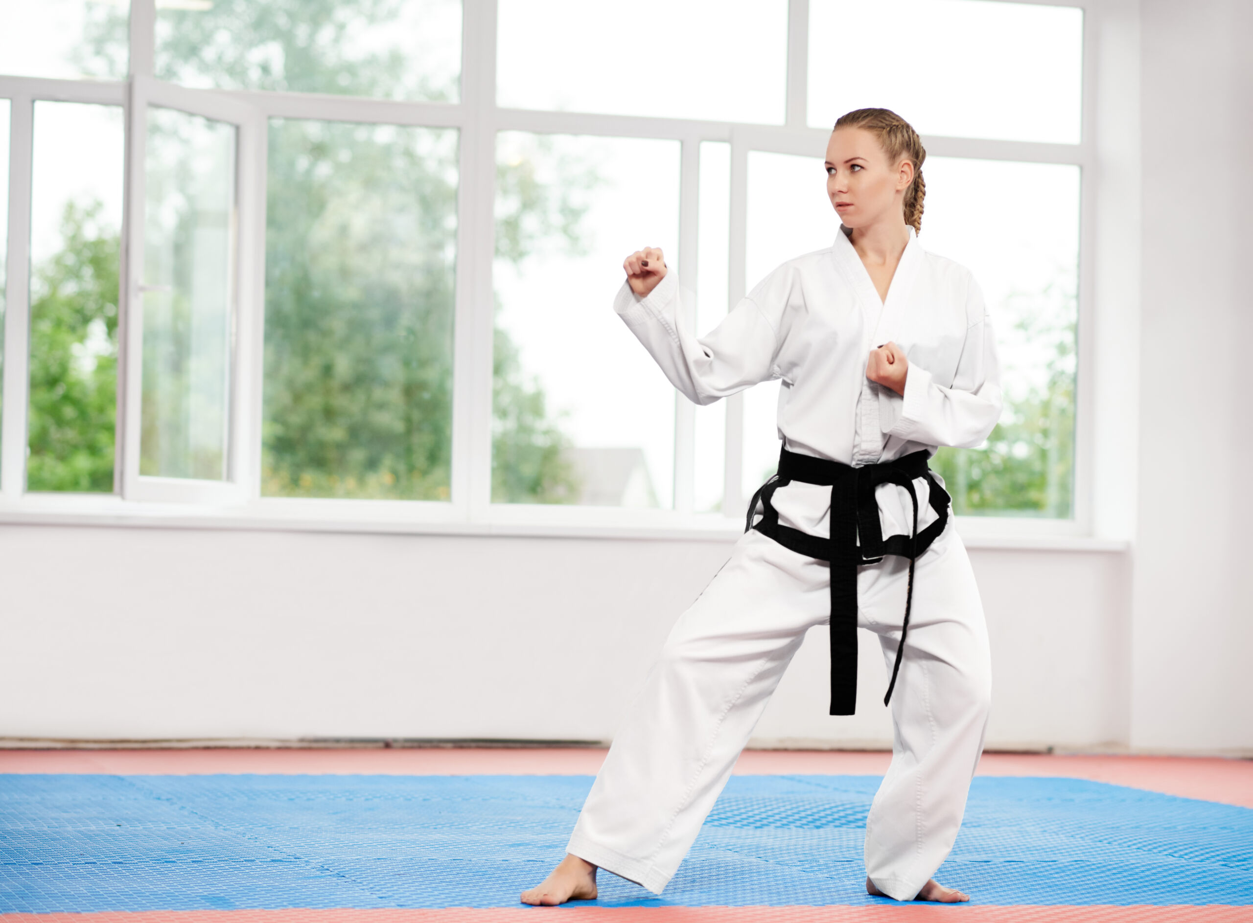 Sporty karate and taekwondo woman in white kimono with black belt.